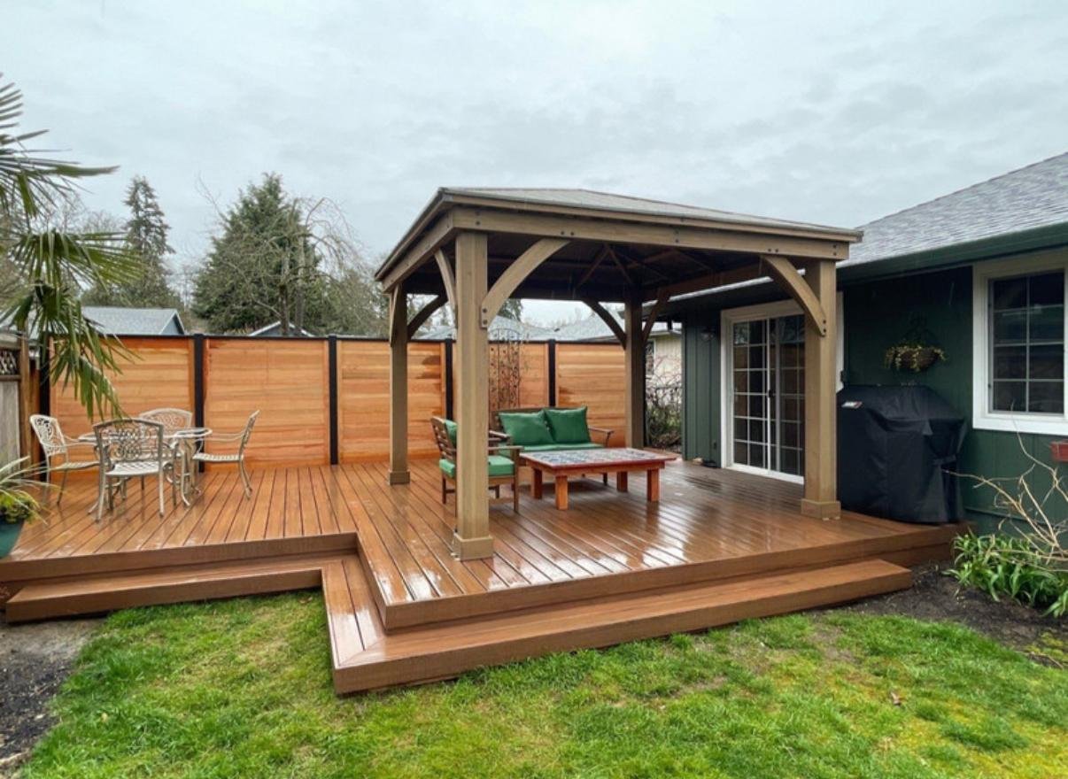 Ground-level wood deck with a covered pavilion and privacy fence